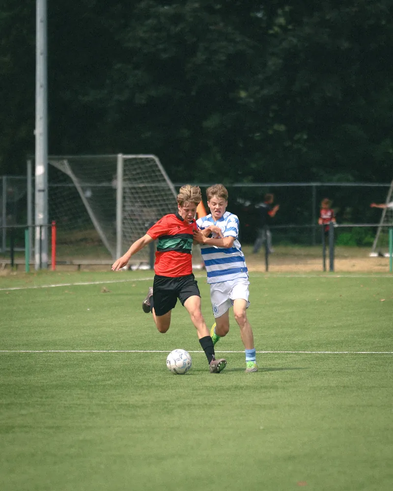 Twee jeugdspelers in duel om de bal tijdens NEC – De Graafschap