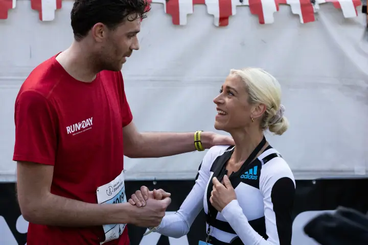 Loper in rood shirt feliciteert de winnares met een stevige handdruk na de finish