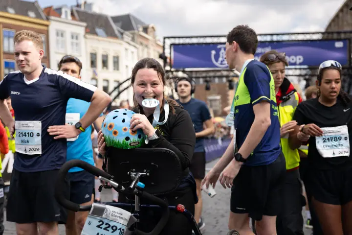 Stralende finisher toont haar medaille en een helm met zonnebloemen tussen andere lopers