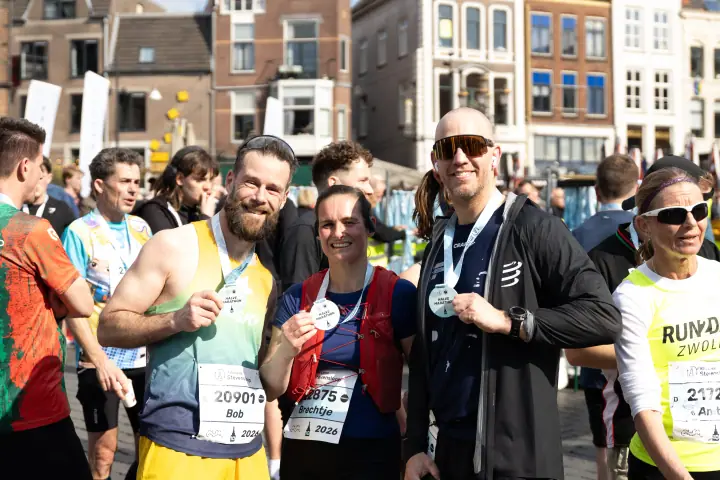 Groepje finishers poseert trots met hun medailles in de binnenstad van Nijmegen