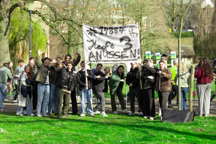 Supporters met een zelfgemaakt spandoek moedigen een loper aan vanaf het gras langs de route