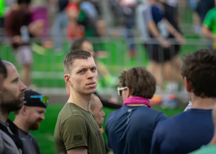 Deelnemer in olijfgroen shirt kijkt over zijn schouder in het drukke startvak