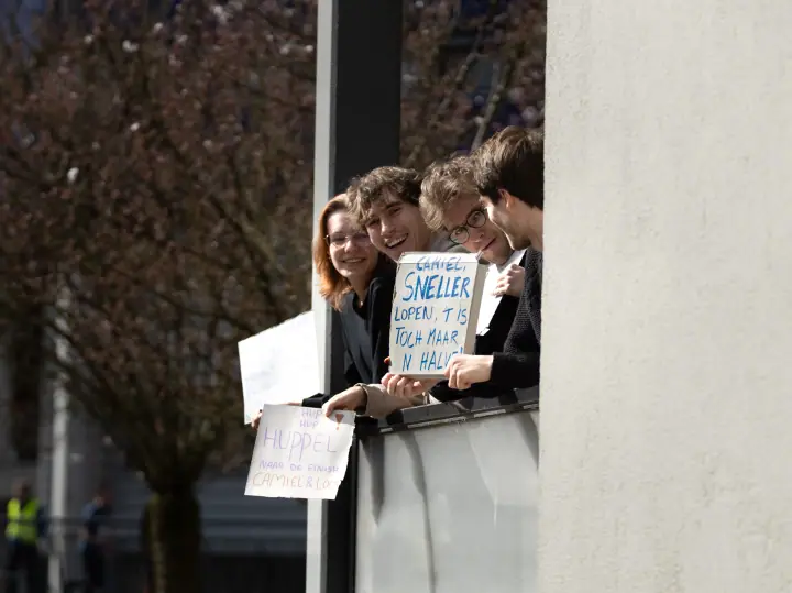 Jongeren op een balkon houden zelfgemaakte bordjes omhoog om een loper aan te moedigen