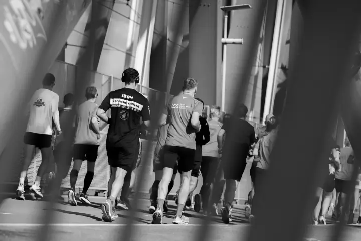 Lopers in zwart-wit van achteren gezien, ingelijst door het staal van de brug