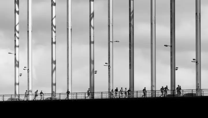Kleine silhouetten van lopers steken een Nijmeegse brug over, onder de hoge stalen hangers