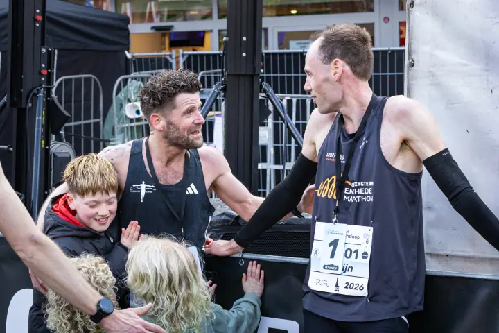 Winnaar en nummer twee schudden elkaar de hand, terwijl kinderen de nummer twee omhelzen