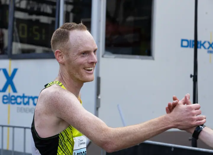 Lachende loper in geel-zwart singlet geeft een high five na zijn finish