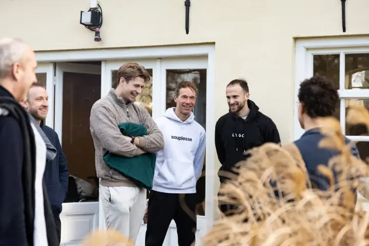 Een moment van ontspanning tussen de oefeningen door, de groep maakt grapjes bij de openslaande deuren.