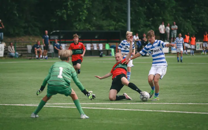 Speler van De Graafschap legt aan voor een schot terwijl een NEC-verdediger een sliding inzet