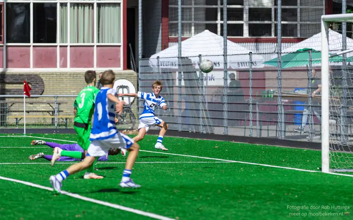 Bal vliegt richting doel na een voorzet, terwijl de keeper op de grond ligt