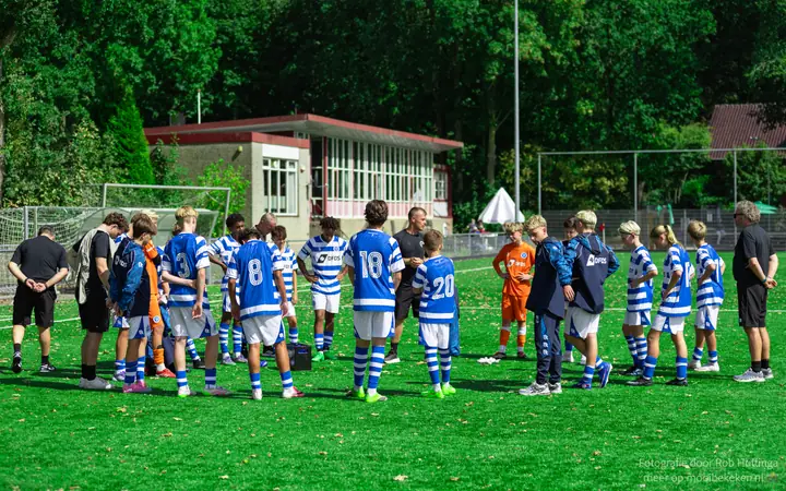 Jeugdteam van De Graafschap luistert in een kring naar de trainer op het veld