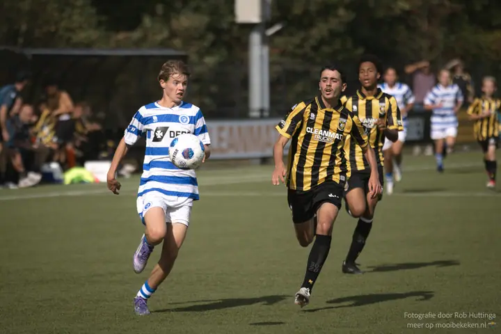 Speler van De Graafschap neemt de bal in de lucht aan, twee Vitesse-spelers sprinten mee