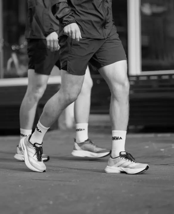 Zwart-witbeeld van twee lopers in korte broek, met de NIMMA sokken als blikvanger