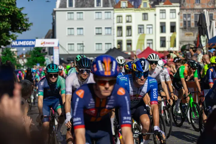 Peloton van het NK Wielrennen 2026 rolt in de zon door de binnenstad van Nijmegen