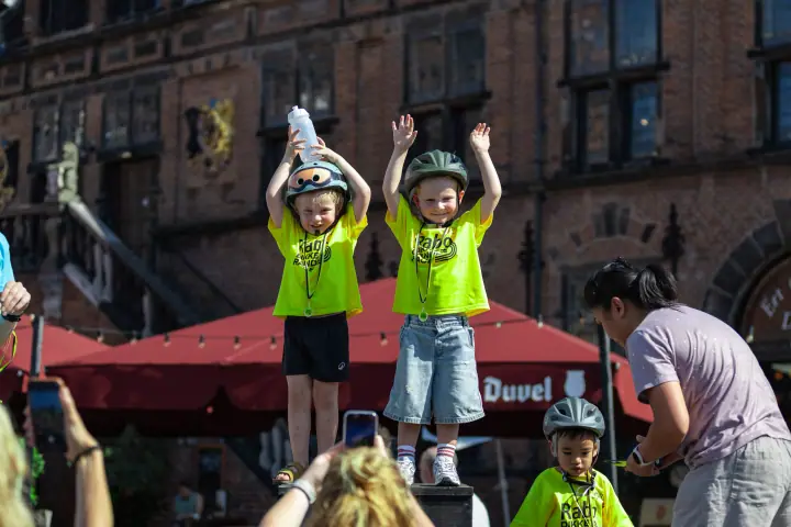 Twee jonge deelnemers juichen met de armen omhoog op het podium voor De Waag