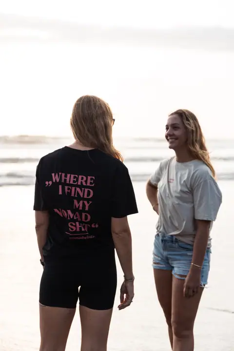 Een vrouw lacht naar haar gesprekspartner, wiens zwarte Nomadwise shirt van achteren in beeld is.