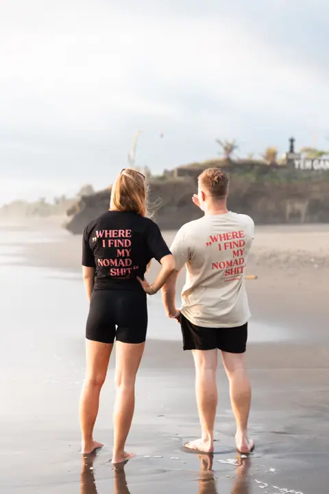 Zij aan zij kijken een vrouw in zwart en een man in beige shirt uit over het strand.