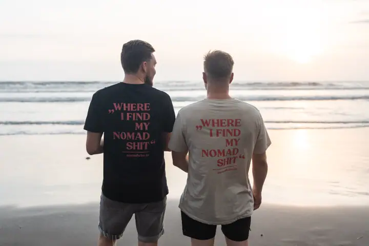 Twee mannen staan schouder aan schouder met hun rug naar de camera, beide Nomadwise prints naast elkaar.