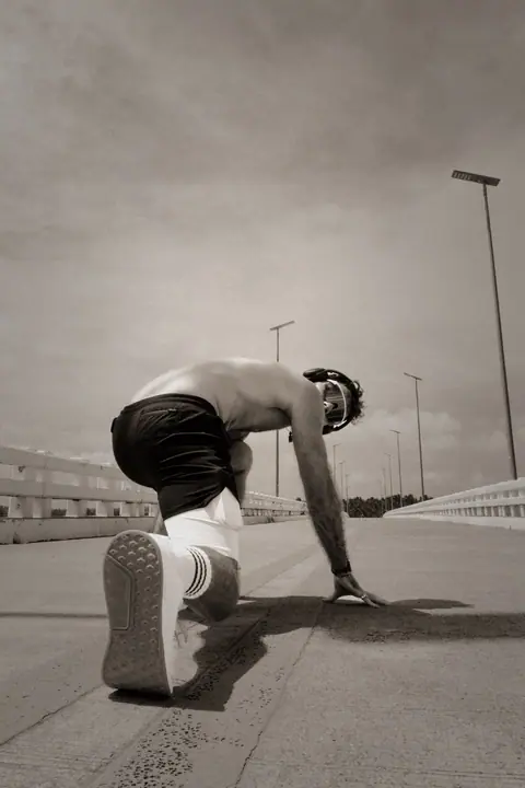 Lukas zit in startpositie op het asfalt van de brug, klaar voor een sprint