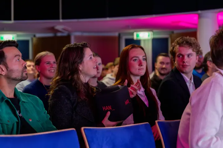 Vrouw in het publiek houdt de zachte HAN gooimicrofoon vast terwijl haar buren meekijken