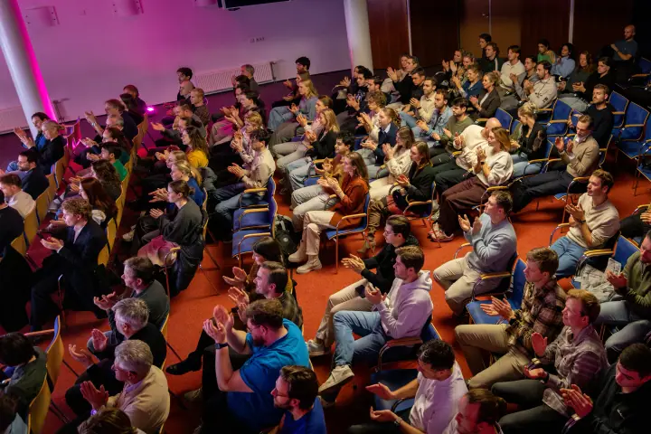 Bovenaanzicht van de volle zaal die enthousiast applaudisseert op de Startup F*ckup Night