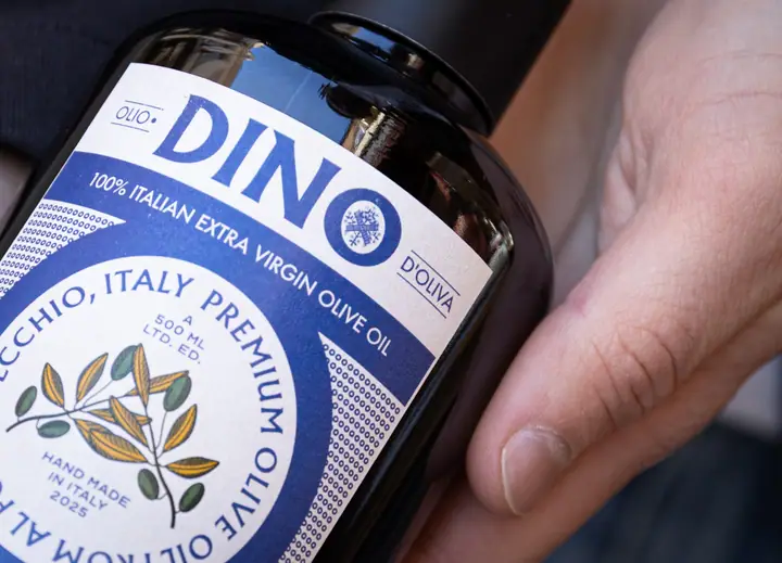 Close-up van het blauwe DINO-etiket op een fles extra vierge olijfolie van Virnelli