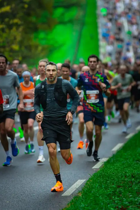 Loper in zwart met oranje schoenen gaat een dicht peloton voor op de route in Nijmegen