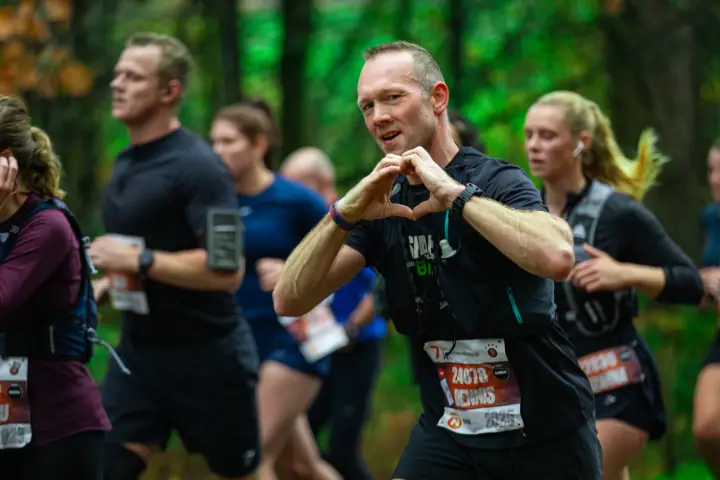 Loper vormt met zijn handen een hartje naar de fotograaf tijdens de Zevenheuvelenloop 2025